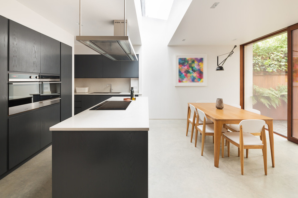 Источник вдохновения для домашнего уюта: кухня среднего размера в стиле модернизм с обеденным столом, двойной мойкой, плоскими фасадами, черными фасадами, техникой из нержавеющей стали, бетонным полом, островом и серым полом