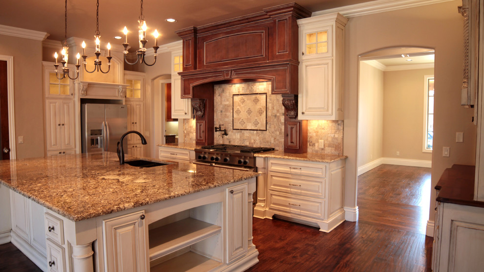 Klassisk inredning av ett mellanstort kök, med en undermonterad diskho, luckor med upphöjd panel, vita skåp, granitbänkskiva, beige stänkskydd, stänkskydd i stenkakel, rostfria vitvaror, vinylgolv och en köksö