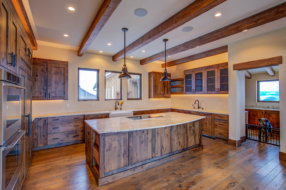 Cette image montre une grande cuisine ouverte encastrable chalet en U et bois brun avec un évier de ferme, un placard avec porte à panneau encastré et îlot.