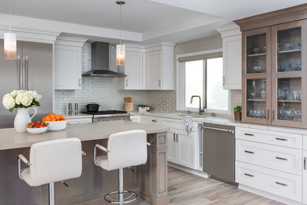 Inspiration for a classic l-shaped open plan kitchen in Orange County with a submerged sink, shaker cabinets, white cabinets, beige splashback, glass tiled splashback, stainless steel appliances, medium hardwood flooring, an island, brown floors, multicoloured worktops and a drop ceiling.