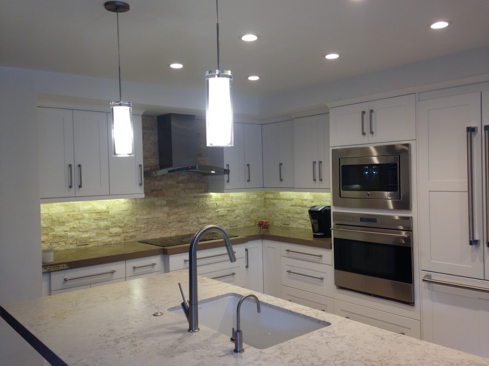 Inspiration for a medium sized contemporary u-shaped kitchen in Orange County with a single-bowl sink, shaker cabinets, white cabinets, engineered stone countertops, beige splashback, stone tiled splashback, stainless steel appliances, porcelain flooring and an island.