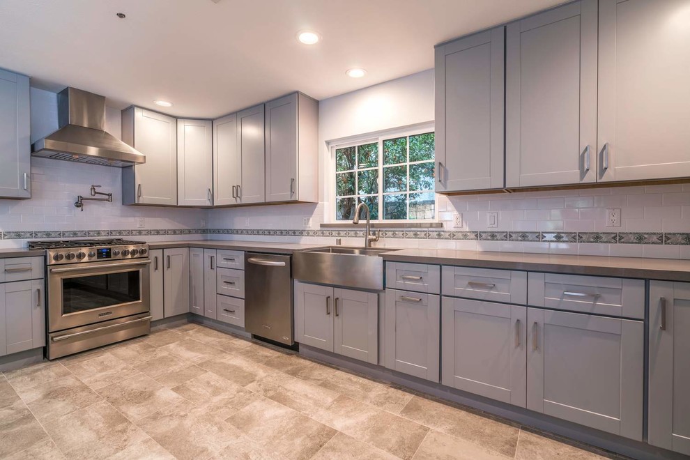 Mid-sized transitional u-shaped porcelain tile and gray floor eat-in kitchen photo in Orange County with a farmhouse sink, recessed-panel cabinets, gray cabinets, quartz countertops, white backsplash, subway tile backsplash, stainless steel appliances, an island and white countertops