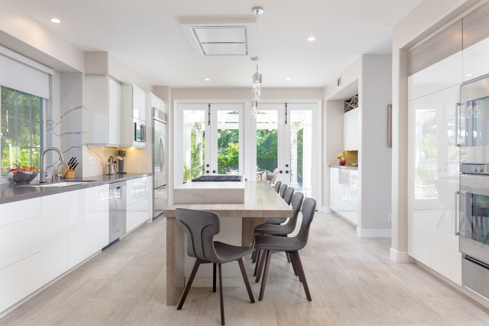 Example of a mid-sized trendy galley gray floor eat-in kitchen design in Orange County with flat-panel cabinets, white cabinets, quartz countertops, white backsplash, stainless steel appliances, an island, gray countertops and an undermount sink