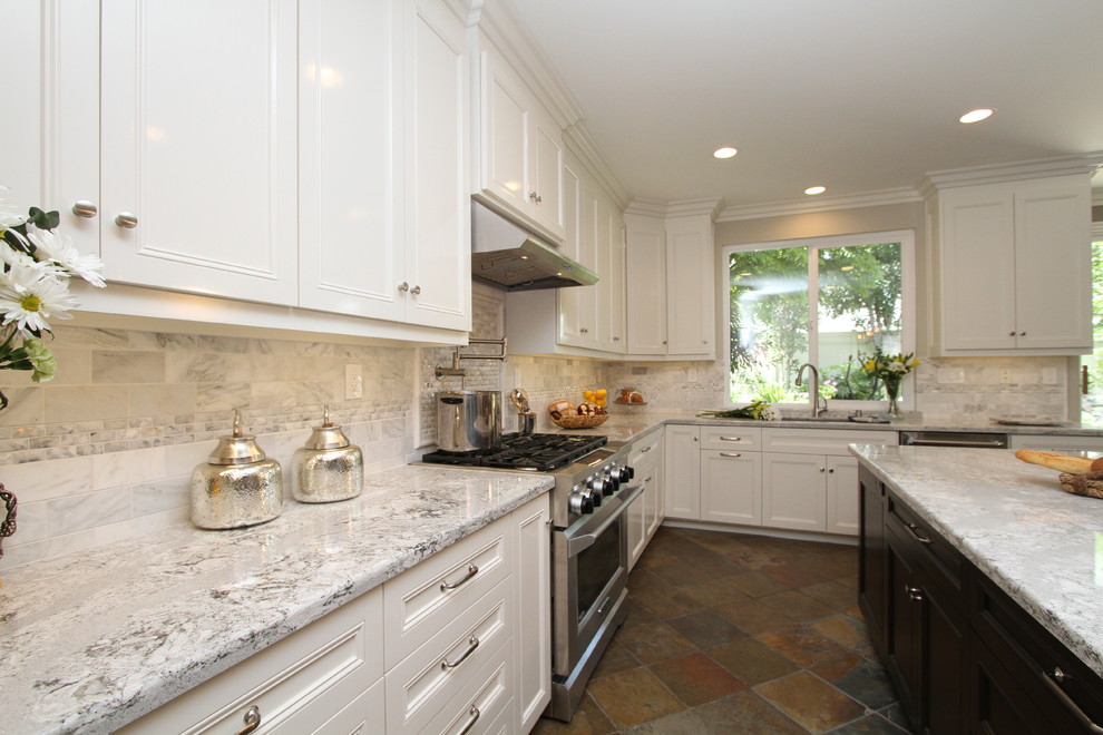 Klassisk inredning av ett mellanstort kök, med en undermonterad diskho, luckor med infälld panel, vita skåp, grått stänkskydd, stänkskydd i tunnelbanekakel, rostfria vitvaror, skiffergolv, en köksö och bänkskiva i kvarts