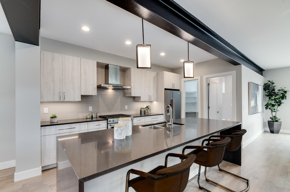 Example of a mid-sized minimalist u-shaped light wood floor and gray floor eat-in kitchen design in Denver with a triple-bowl sink, flat-panel cabinets, light wood cabinets, quartz countertops, gray backsplash, subway tile backsplash, stainless steel appliances, an island and gray countertops