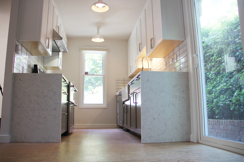 Inspiration for a small modern galley medium tone wood floor and brown floor eat-in kitchen remodel in Portland with an undermount sink, shaker cabinets, white cabinets, marble countertops, white backsplash, subway tile backsplash, stainless steel appliances and no island