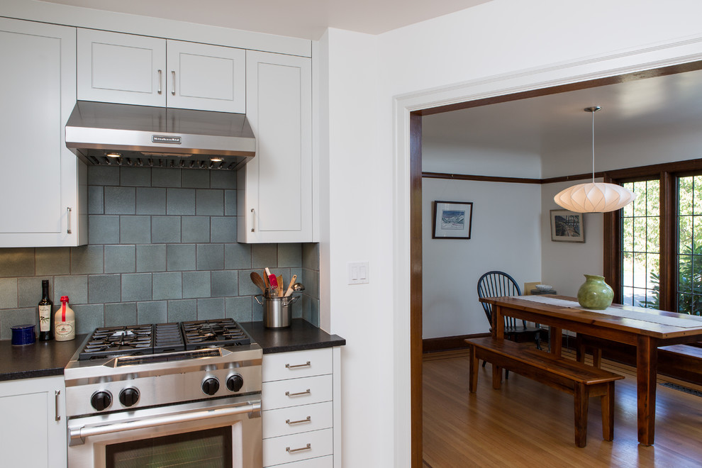 Kleine Klassische Wohnküche in U-Form mit Landhausspüle, weißen Schränken, Granit-Arbeitsplatte, Küchenrückwand in Blau, Rückwand aus Keramikfliesen, Küchengeräten aus Edelstahl und hellem Holzboden in Portland