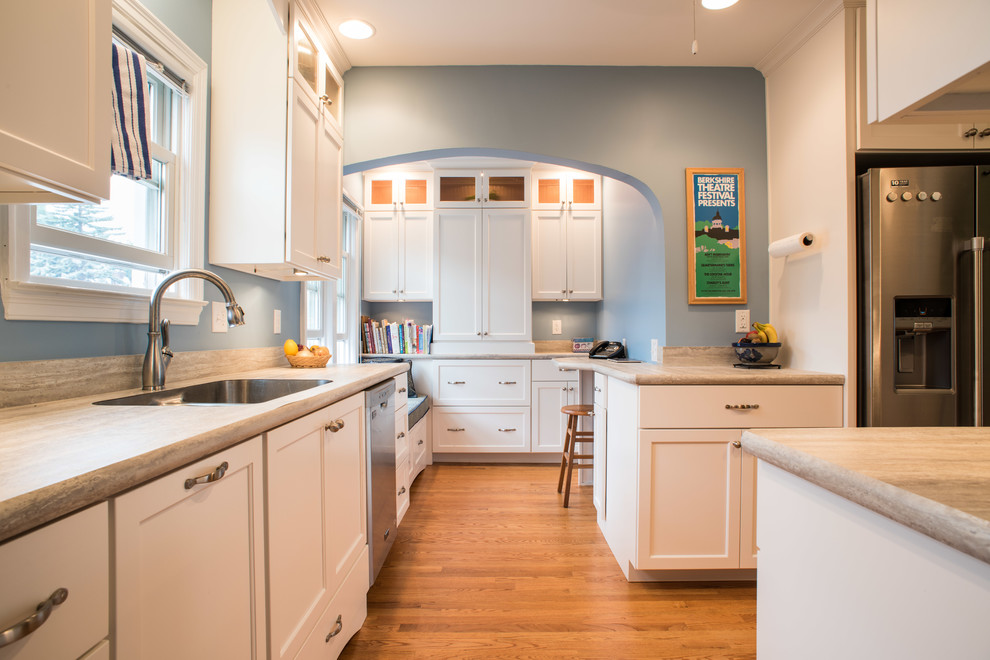 Bild på ett avskilt, mellanstort funkis parallellkök, med en rustik diskho, luckor med infälld panel, vita skåp, marmorbänkskiva, blått stänkskydd, rostfria vitvaror, mellanmörkt trägolv och en halv köksö