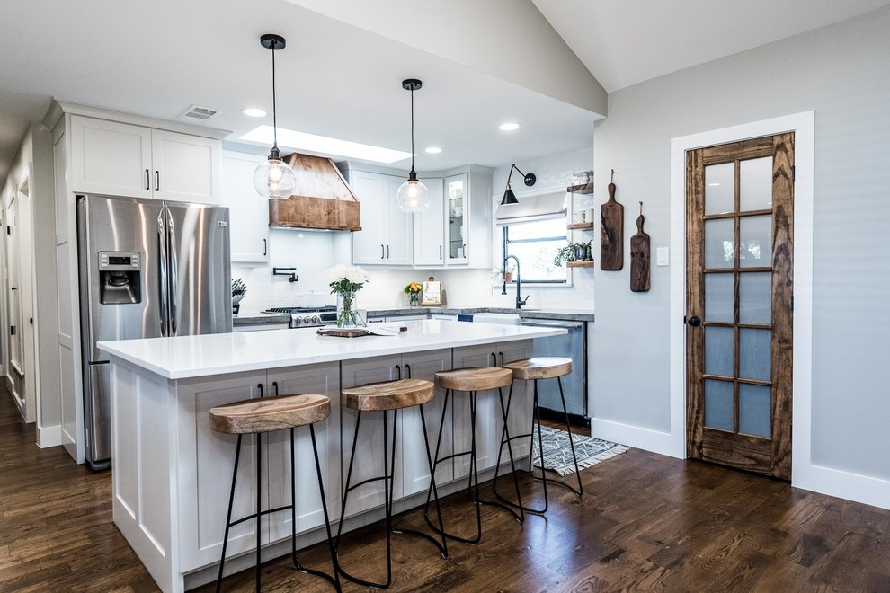 Bild på ett mellanstort lantligt grå grått kök, med en rustik diskho, skåp i shakerstil, vita skåp, bänkskiva i betong, vitt stänkskydd, stänkskydd i keramik, rostfria vitvaror, mellanmörkt trägolv, en köksö och brunt golv