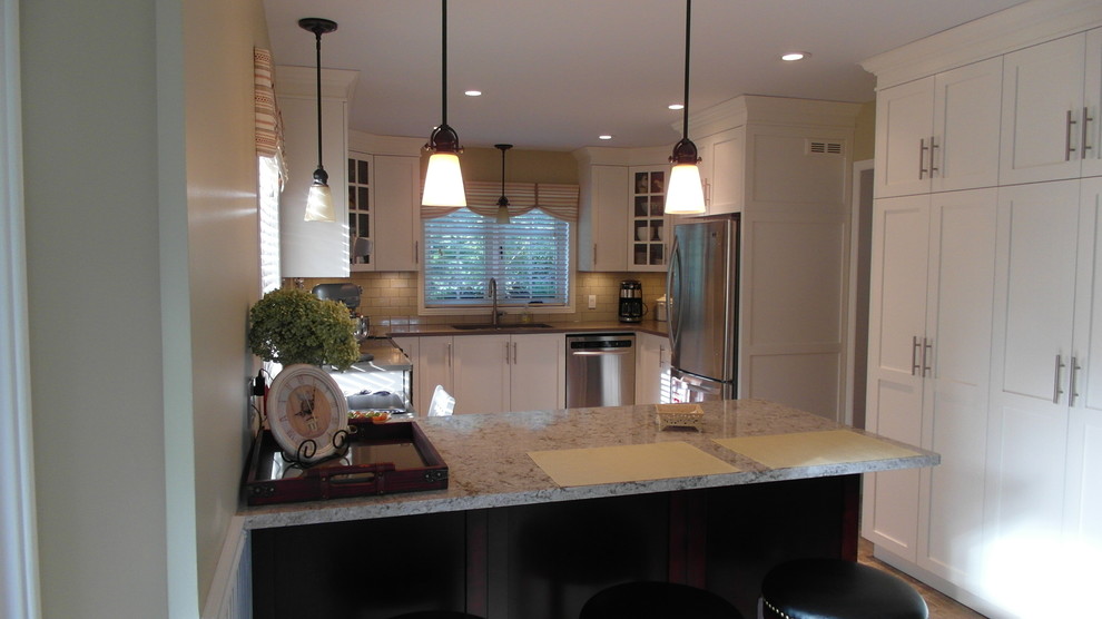 Foto på ett mellanstort funkis kök, med en undermonterad diskho, skåp i shakerstil, vita skåp, granitbänkskiva, grått stänkskydd, stänkskydd i tunnelbanekakel, rostfria vitvaror, en halv köksö, klinkergolv i keramik och brunt golv