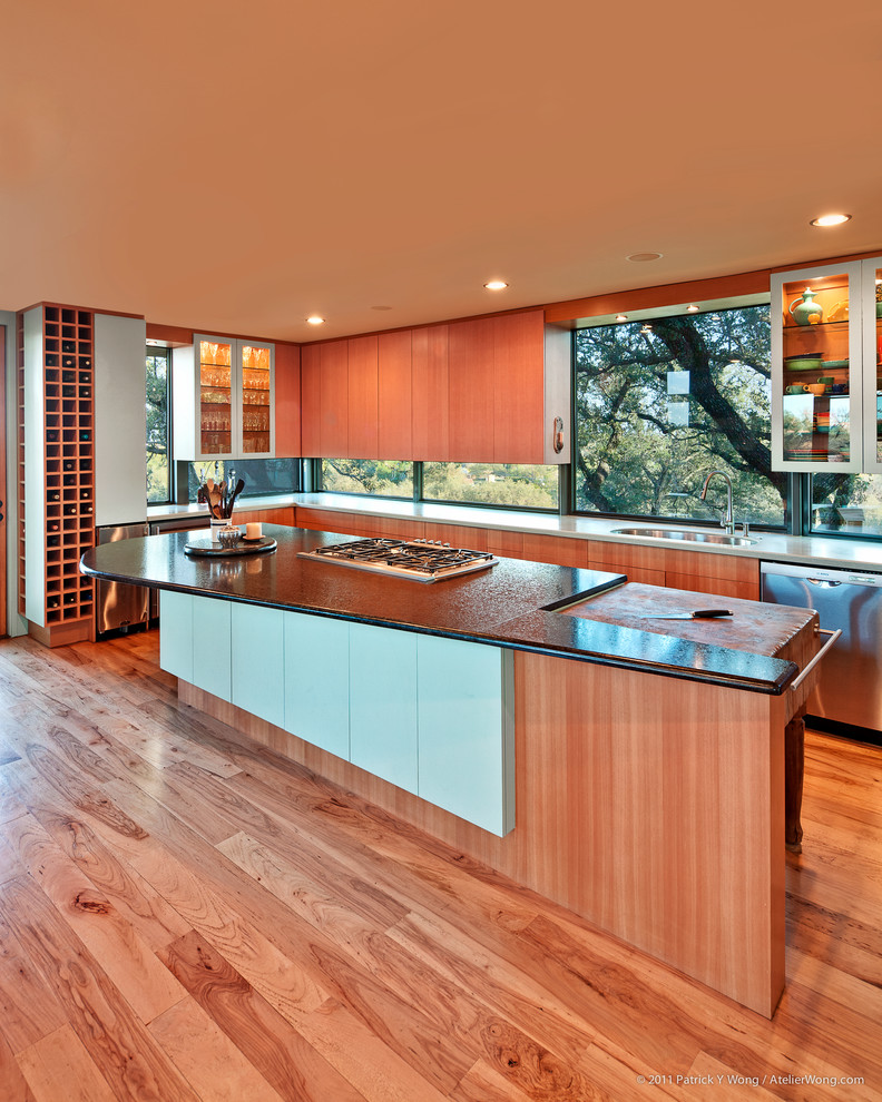 Réalisation d'une grande cuisine ouverte design en L et bois brun avec un évier 1 bac, un placard à porte plane, un électroménager en acier inoxydable, un sol en bois brun, îlot, fenêtre et un sol marron.