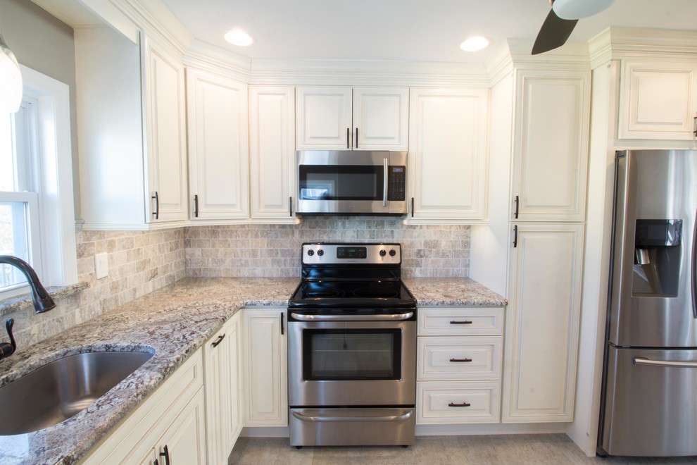 Bild på ett mellanstort vintage kök, med en undermonterad diskho, luckor med upphöjd panel, vita skåp, granitbänkskiva, grått stänkskydd, stänkskydd i tunnelbanekakel, rostfria vitvaror och klinkergolv i porslin