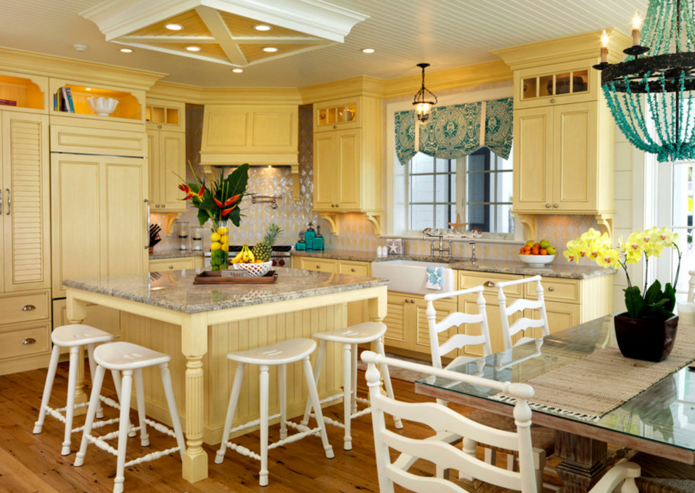 Foto på ett maritimt kök, med en rustik diskho, gula skåp, flerfärgad stänkskydd, rostfria vitvaror och en köksö