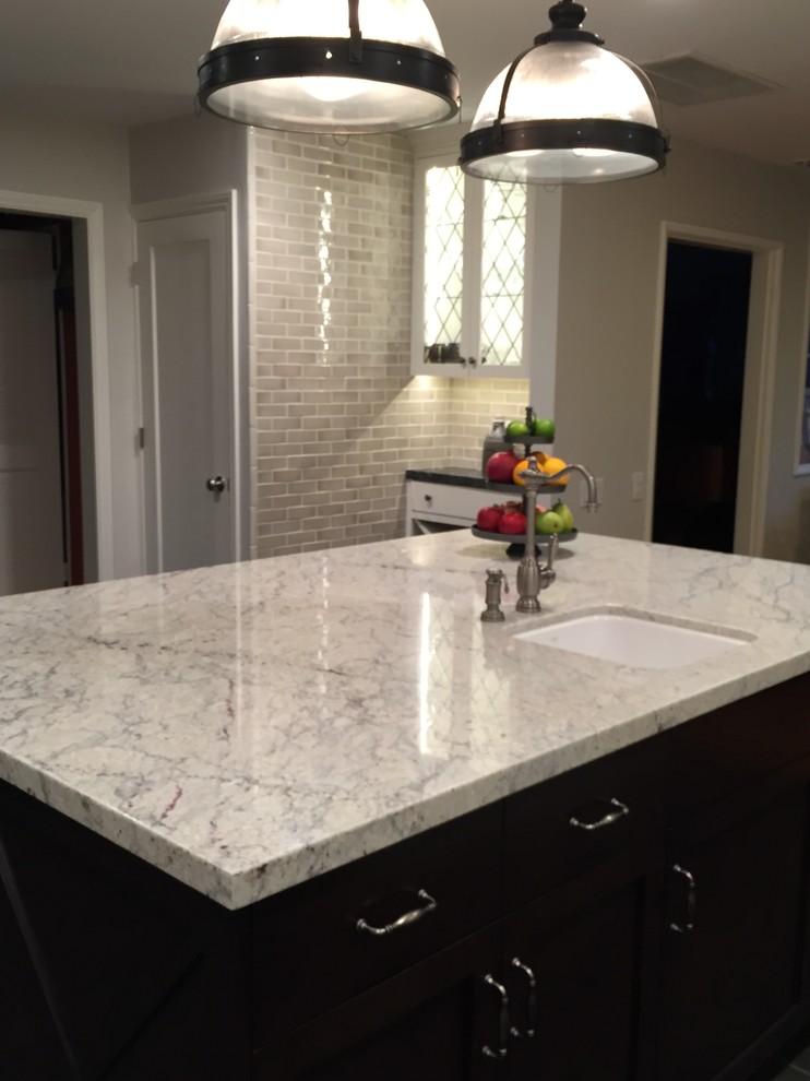 Example of a large transitional ceramic tile kitchen design in Los Angeles with a farmhouse sink, shaker cabinets, white cabinets, marble countertops, beige backsplash, subway tile backsplash, stainless steel appliances and an island