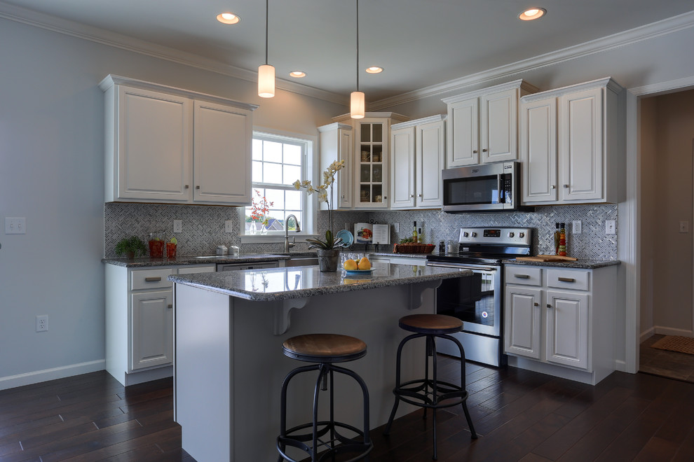 Open concept kitchen - mid-sized farmhouse l-shaped dark wood floor and brown floor open concept kitchen idea in Other with a farmhouse sink, raised-panel cabinets, white cabinets, granite countertops, gray backsplash, mosaic tile backsplash, stainless steel appliances and an island