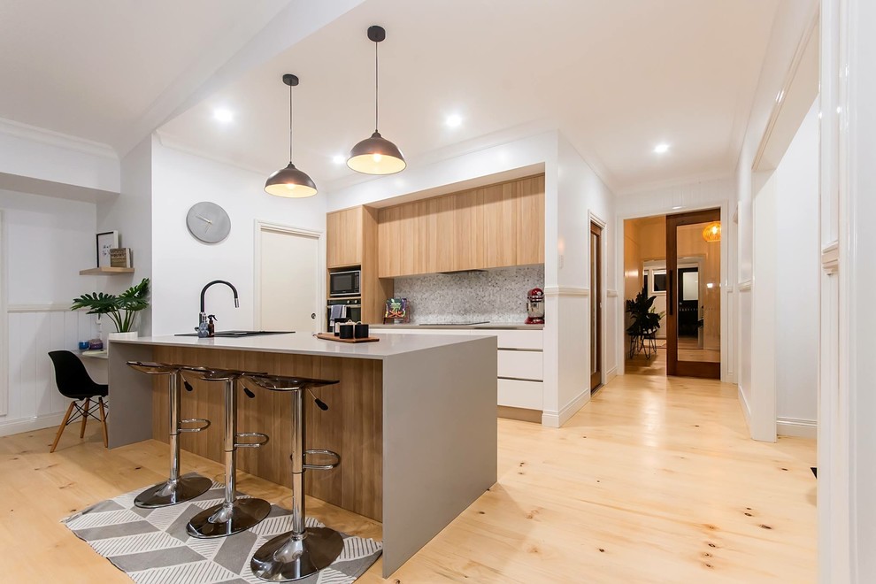 Inspiration for an expansive modern galley enclosed kitchen in Brisbane with a submerged sink, white cabinets, granite worktops, stainless steel appliances, light hardwood flooring, an island and white worktops.