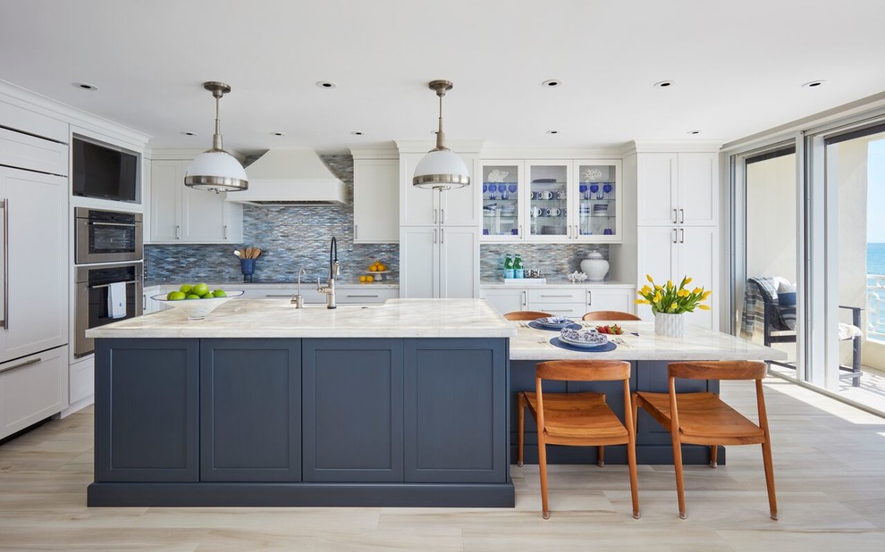 Foto di un cucina con isola centrale stile marinaro con ante in stile shaker, ante bianche, paraspruzzi blu, paraspruzzi con piastrelle a mosaico, elettrodomestici da incasso, pavimento beige e top bianco