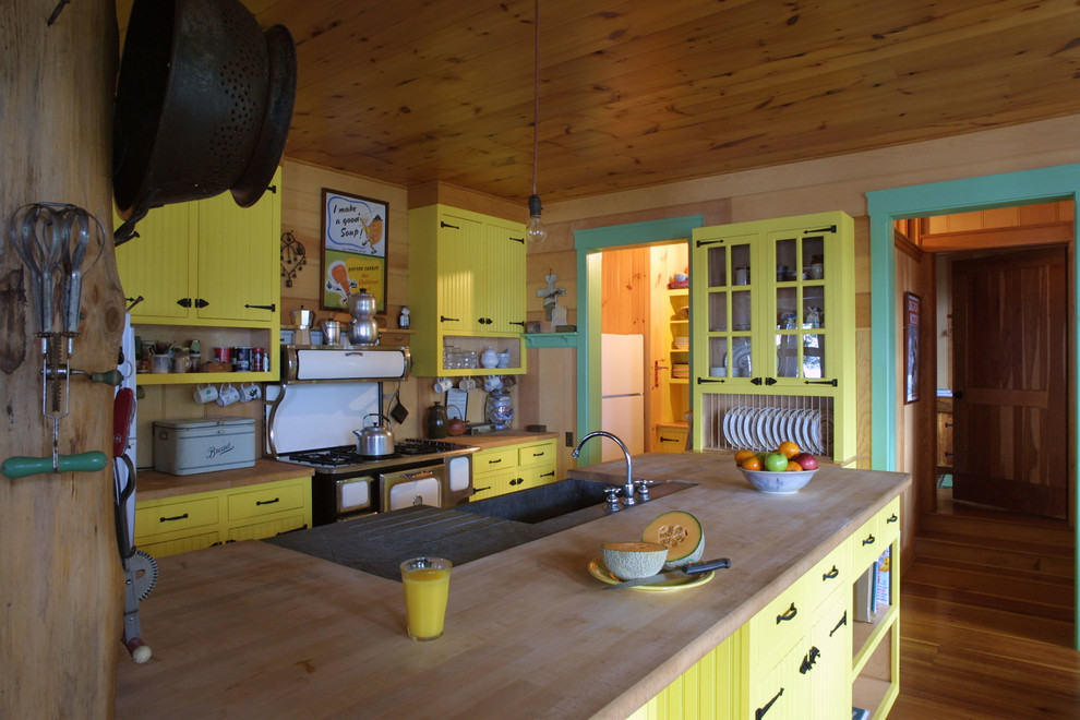 Eat-in kitchen - mid-sized eclectic l-shaped dark wood floor and brown floor eat-in kitchen idea in New York with a farmhouse sink, flat-panel cabinets, yellow cabinets, wood countertops and a peninsula