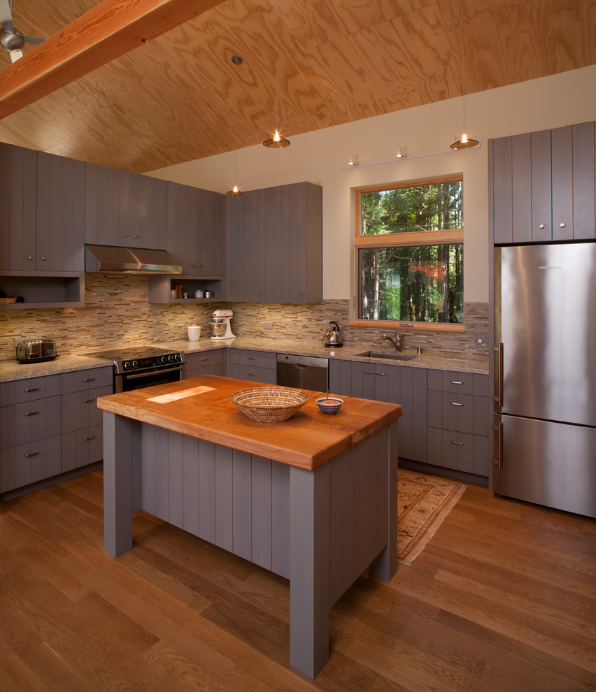 Example of a mid-sized cottage u-shaped medium tone wood floor eat-in kitchen design in Seattle with an undermount sink, louvered cabinets, gray cabinets, granite countertops, beige backsplash, matchstick tile backsplash, stainless steel appliances and an island