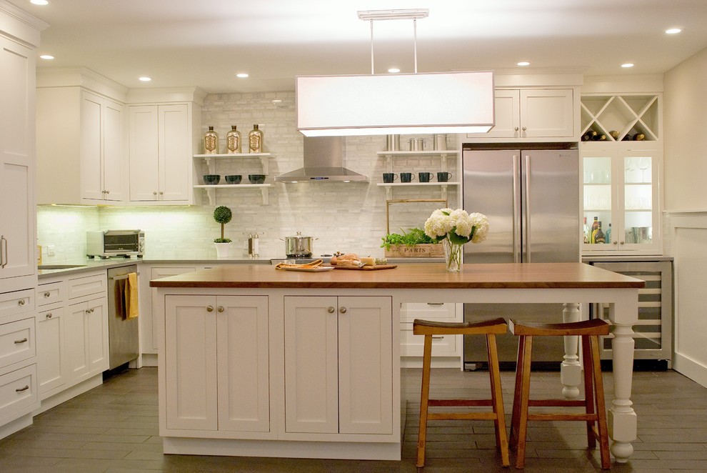 Diseño de cocinas en L clásica con electrodomésticos de acero inoxidable, encimera de madera, armarios estilo shaker y puertas de armario blancas