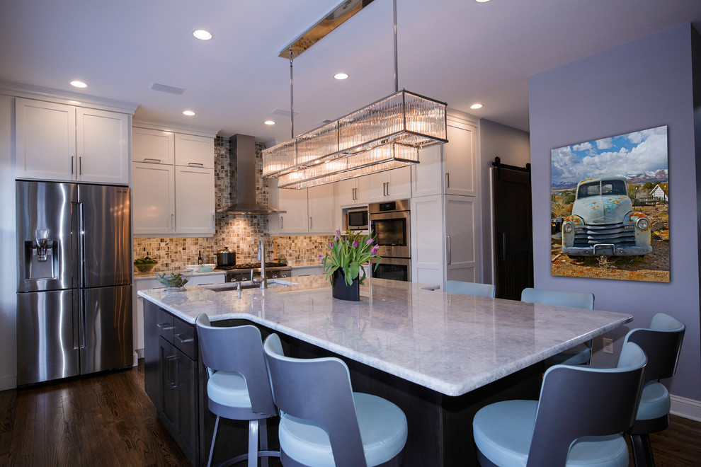 Mid-sized transitional medium tone wood floor open concept kitchen photo in Philadelphia with an undermount sink, white cabinets, quartzite countertops, multicolored backsplash, mosaic tile backsplash, stainless steel appliances and two islands