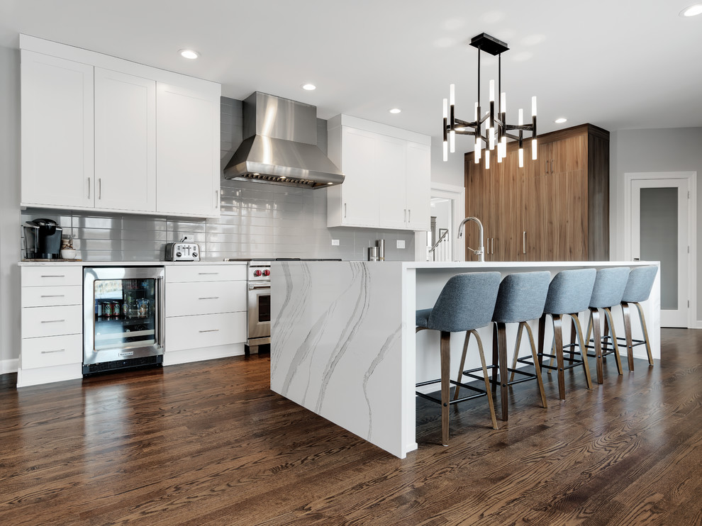 Enclosed kitchen - large modern l-shaped medium tone wood floor and brown floor enclosed kitchen idea in Chicago with an undermount sink, flat-panel cabinets, white cabinets, quartz countertops, gray backsplash, porcelain backsplash, paneled appliances, an island and white countertops