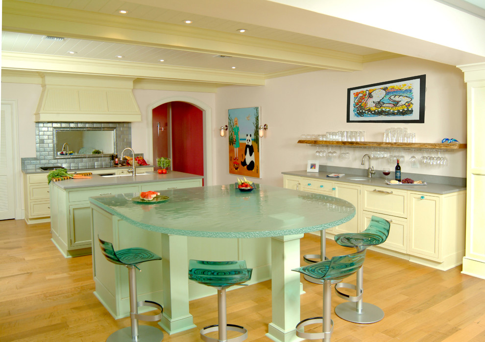 Foto på ett stort funkis kök, med bänkskiva i glas, en undermonterad diskho, skåp i shakerstil, vita skåp, vitt stänkskydd, rostfria vitvaror, ljust trägolv och en köksö