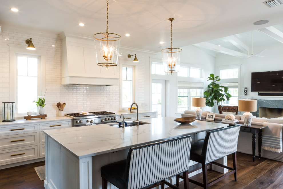 Design ideas for a classic l-shaped open plan kitchen in Tampa with a submerged sink, shaker cabinets, white cabinets, white splashback, metro tiled splashback, dark hardwood flooring, an island, brown floors and white worktops.