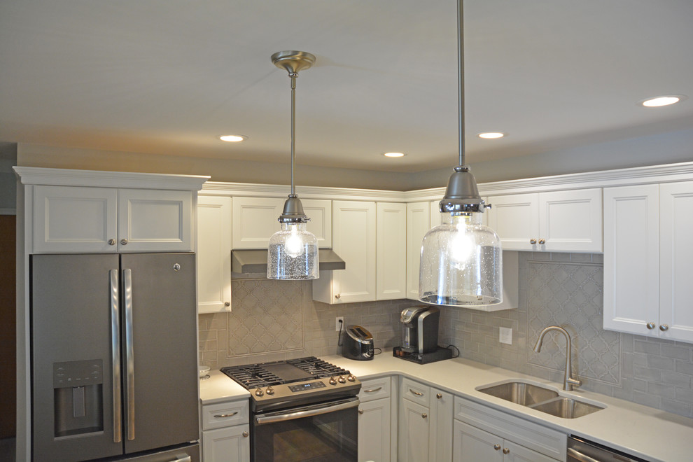 Exempel på ett mellanstort klassiskt vit vitt kök, med en dubbel diskho, luckor med infälld panel, grå skåp, bänkskiva i kvarts, grått stänkskydd, stänkskydd i keramik, rostfria vitvaror, vinylgolv, en köksö och brunt golv