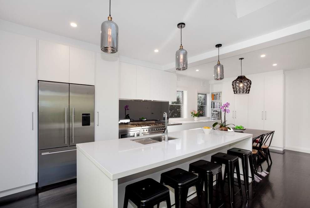 Eat-in kitchen - large contemporary galley dark wood floor eat-in kitchen idea in Sydney with a double-bowl sink, flat-panel cabinets, white cabinets, laminate countertops, black backsplash, glass tile backsplash, stainless steel appliances and an island