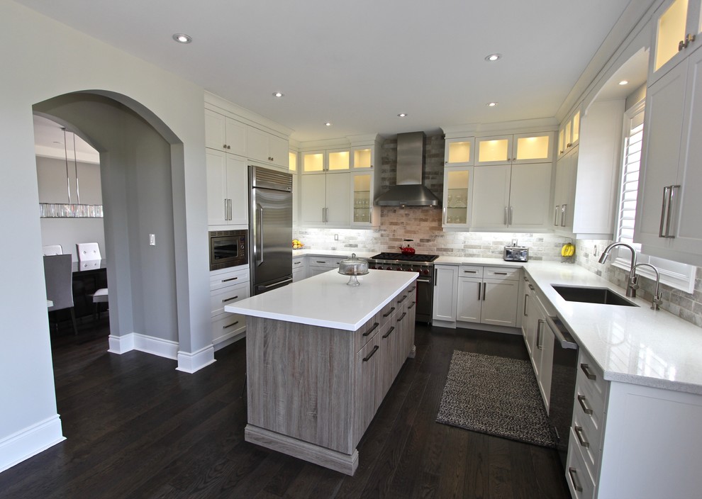Inspiration for a large classic u-shaped open plan kitchen in Toronto with a submerged sink, shaker cabinets, white cabinets, engineered stone countertops, grey splashback, stone tiled splashback, stainless steel appliances, dark hardwood flooring and an island.