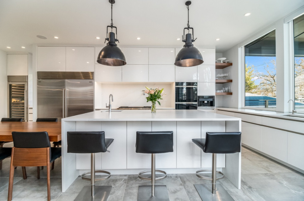 Eat-in kitchen - large contemporary u-shaped porcelain tile and gray floor eat-in kitchen idea in Chicago with flat-panel cabinets, white cabinets, quartz countertops, white backsplash, quartz backsplash, stainless steel appliances, an island and white countertops