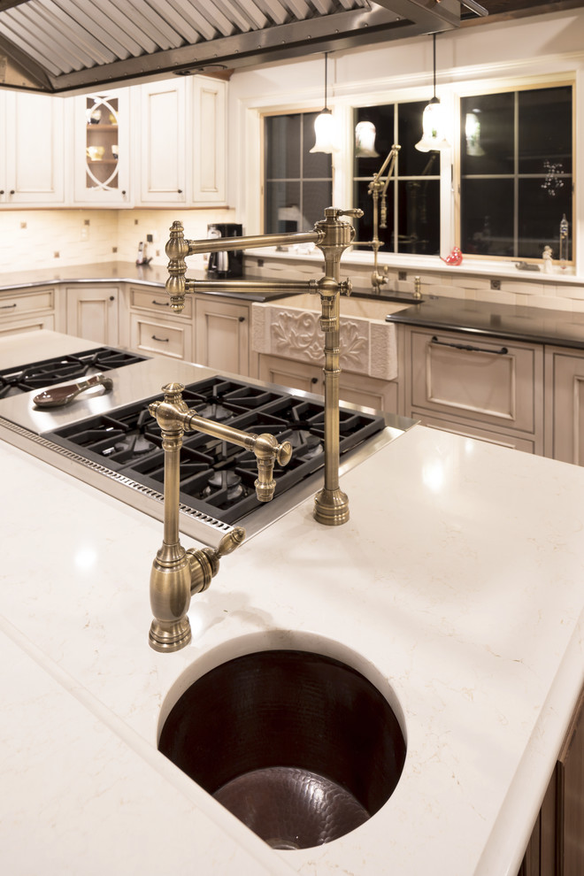 Rustik inredning av ett stort kök, med en rustik diskho, luckor med profilerade fronter, vita skåp, granitbänkskiva, vitt stänkskydd, stänkskydd i marmor, integrerade vitvaror, en köksö och rött golv