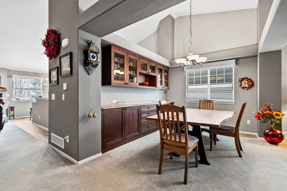 Immagine di una sala da pranzo aperta verso la cucina tradizionale di medie dimensioni con pareti grigie, moquette, nessun camino, pavimento grigio e soffitto a volta