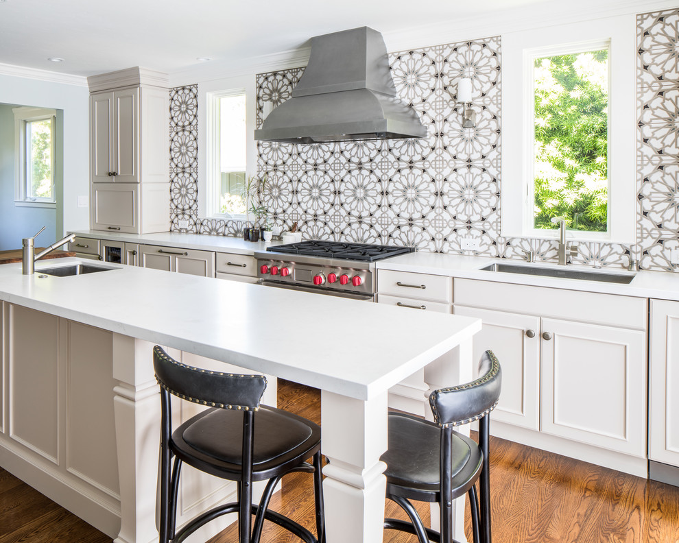 Inspiration for a transitional galley medium tone wood floor and brown floor kitchen remodel in San Francisco with an undermount sink, recessed-panel cabinets, white cabinets, multicolored backsplash, stainless steel appliances, an island and white countertops