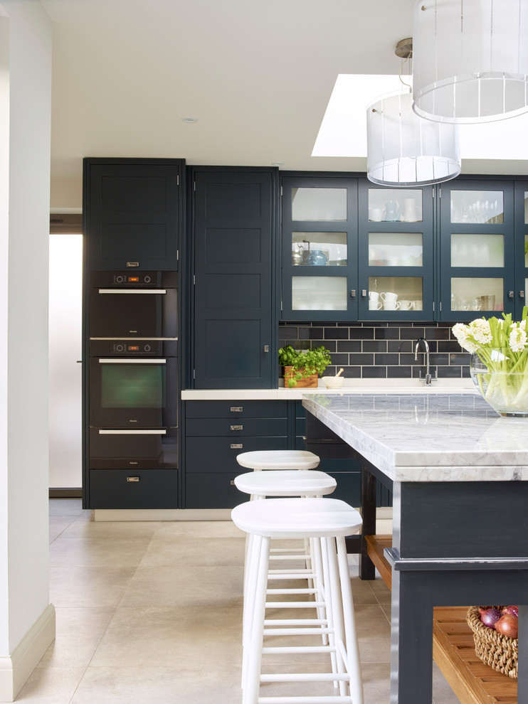ロンドンにある高級な広いコンテンポラリースタイルのおしゃれなキッチン (人工大理石カウンター、ガラス板のキッチンパネル、シルバーの調理設備、磁器タイルの床) の写真