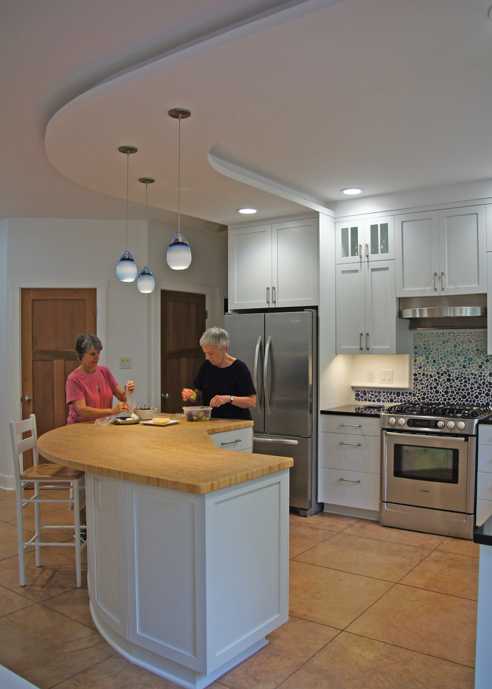 This is an example of a contemporary kitchen/diner in Raleigh with a submerged sink, shaker cabinets, white cabinets, engineered stone countertops, blue splashback, stone tiled splashback, stainless steel appliances, concrete flooring and an island.
