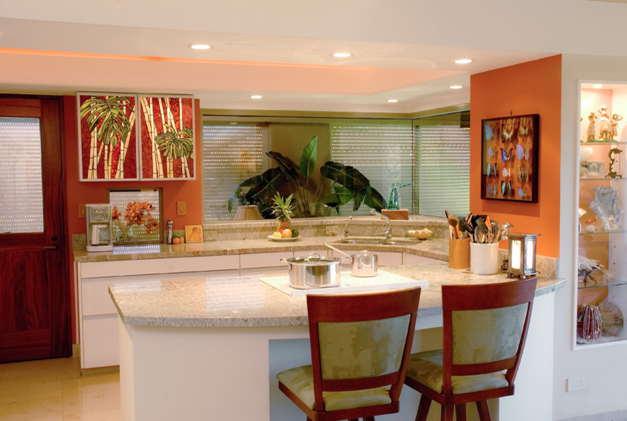ハワイにあるラグジュアリーな中くらいなトロピカルスタイルのおしゃれなキッチン (アンダーカウンターシンク、ガラス扉のキャビネット、御影石カウンター、白い調理設備、白いキャビネット、大理石の床) の写真