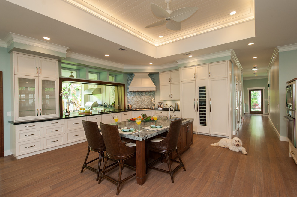 Large traditional l-shaped open plan kitchen in Hawaii with a submerged sink, shaker cabinets, white cabinets, soapstone worktops, blue splashback, glass sheet splashback, integrated appliances, bamboo flooring and an island.