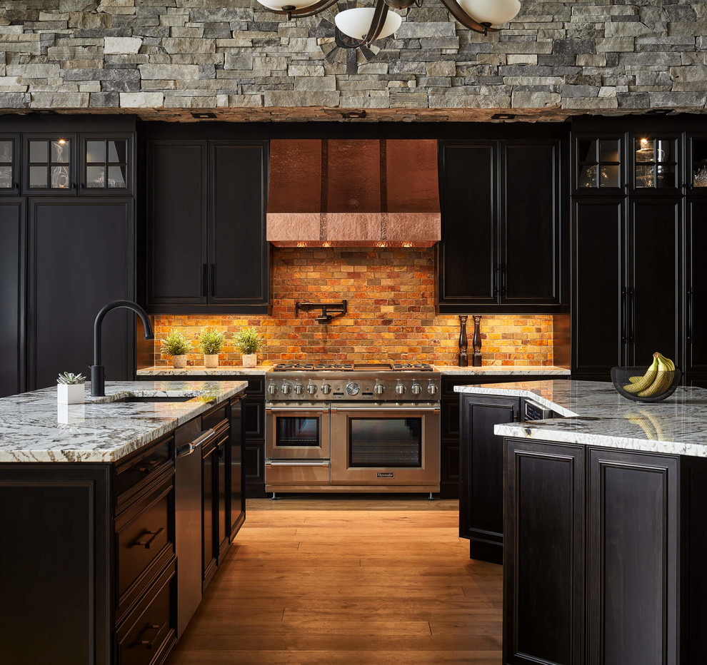 Inspiration för ett stort rustikt grå grått kök, med luckor med upphöjd panel, granitbänkskiva, rostfria vitvaror, flera köksöar, en undermonterad diskho, svarta skåp, orange stänkskydd, stänkskydd i tegel, mellanmörkt trägolv och brunt golv