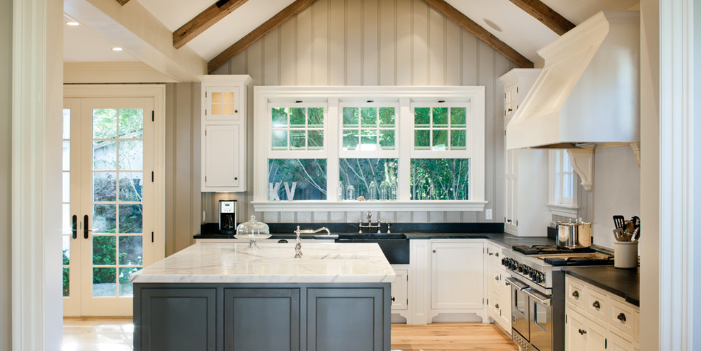 Inspiration for a mid-sized timeless l-shaped light wood floor open concept kitchen remodel in Boston with a farmhouse sink, beaded inset cabinets, white cabinets, stainless steel appliances, granite countertops and an island
