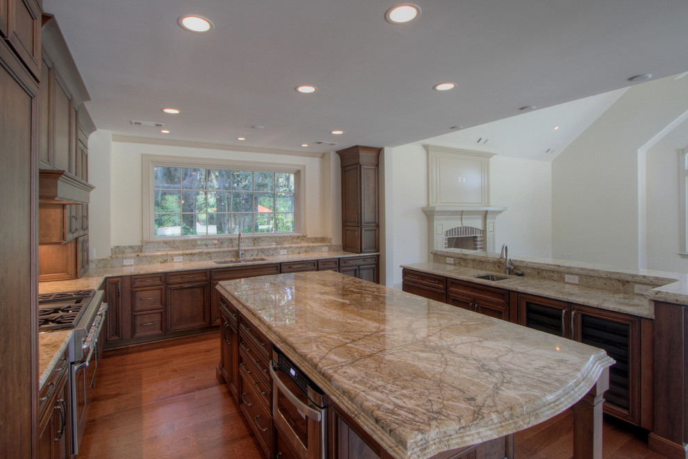 Design ideas for an expansive traditional u-shaped open plan kitchen in Atlanta with a submerged sink, flat-panel cabinets, medium wood cabinets, granite worktops, stone slab splashback, integrated appliances, medium hardwood flooring and multiple islands.