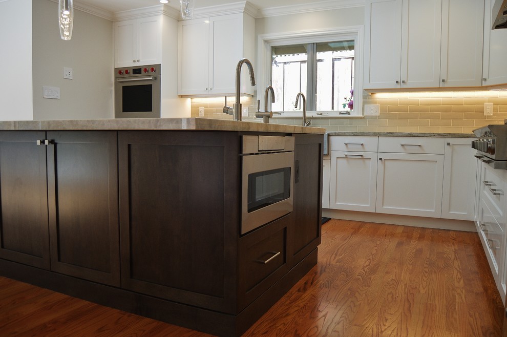 Inspiration for a large contemporary l-shaped medium tone wood floor and brown floor open concept kitchen remodel in San Francisco with a farmhouse sink, shaker cabinets, white cabinets, quartzite countertops, gray backsplash, subway tile backsplash, stainless steel appliances and an island