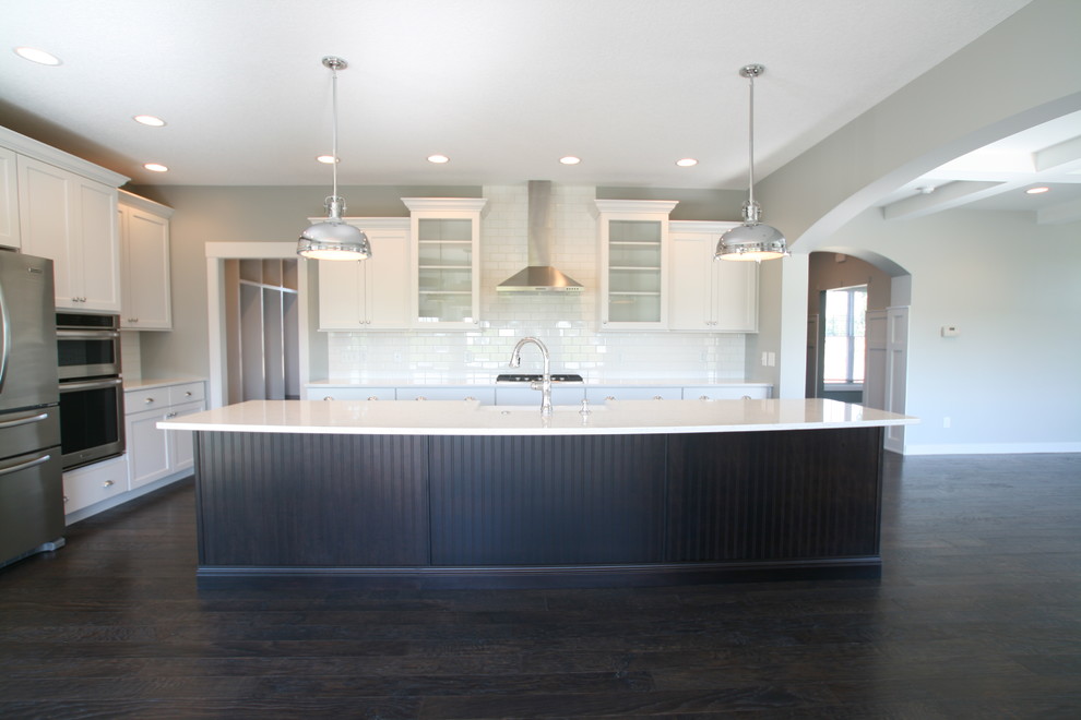Example of a classic l-shaped eat-in kitchen design in Chicago with a farmhouse sink, flat-panel cabinets, dark wood cabinets, quartz countertops and stainless steel appliances