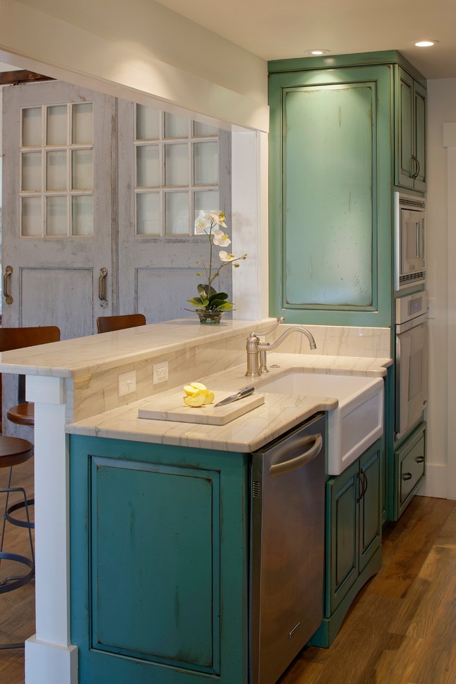 Inspiration for a large coastal galley medium tone wood floor eat-in kitchen remodel in Atlanta with a farmhouse sink, raised-panel cabinets, green cabinets, quartzite countertops, multicolored backsplash, ceramic backsplash, white appliances and no island