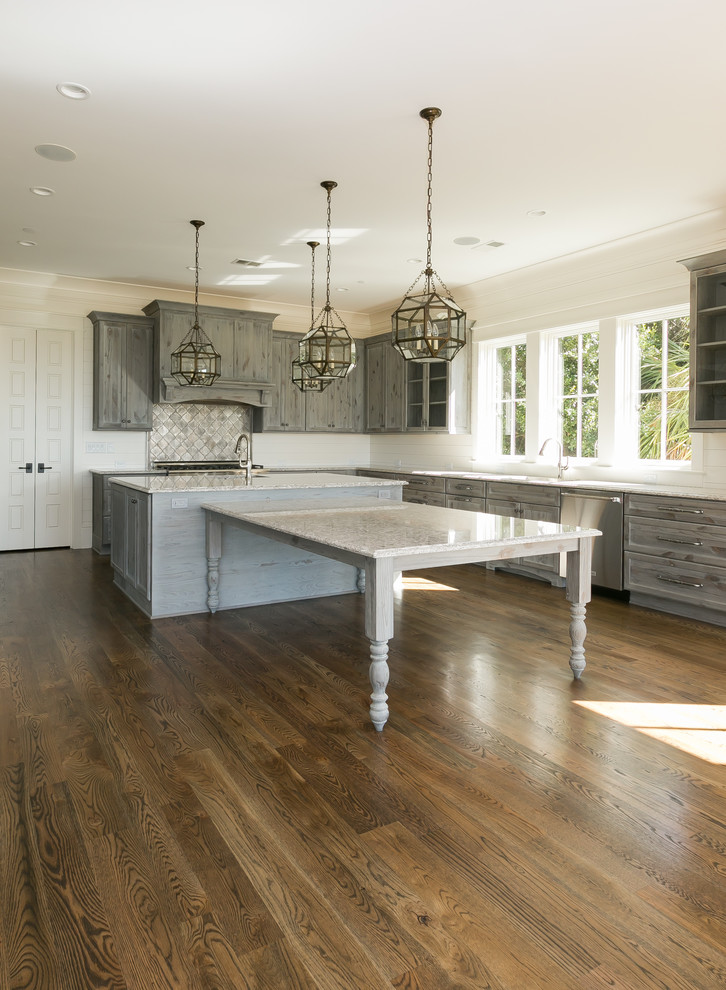 Photo of a large beach style u-shaped kitchen in Charleston with a submerged sink, shaker cabinets, distressed cabinets, engineered stone countertops, grey splashback, mosaic tiled splashback, stainless steel appliances, medium hardwood flooring and an island.