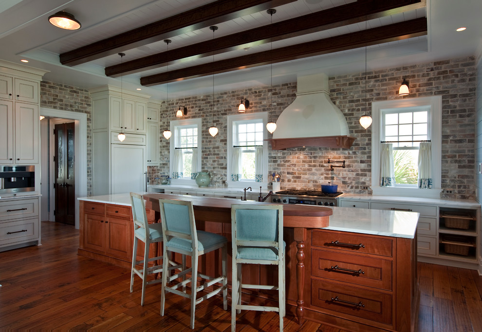 Maritime Küche in L-Form mit Schrankfronten mit vertiefter Füllung, weißen Schränken, bunter Rückwand, Küchengeräten aus Edelstahl, braunem Holzboden und Kücheninsel in Charleston