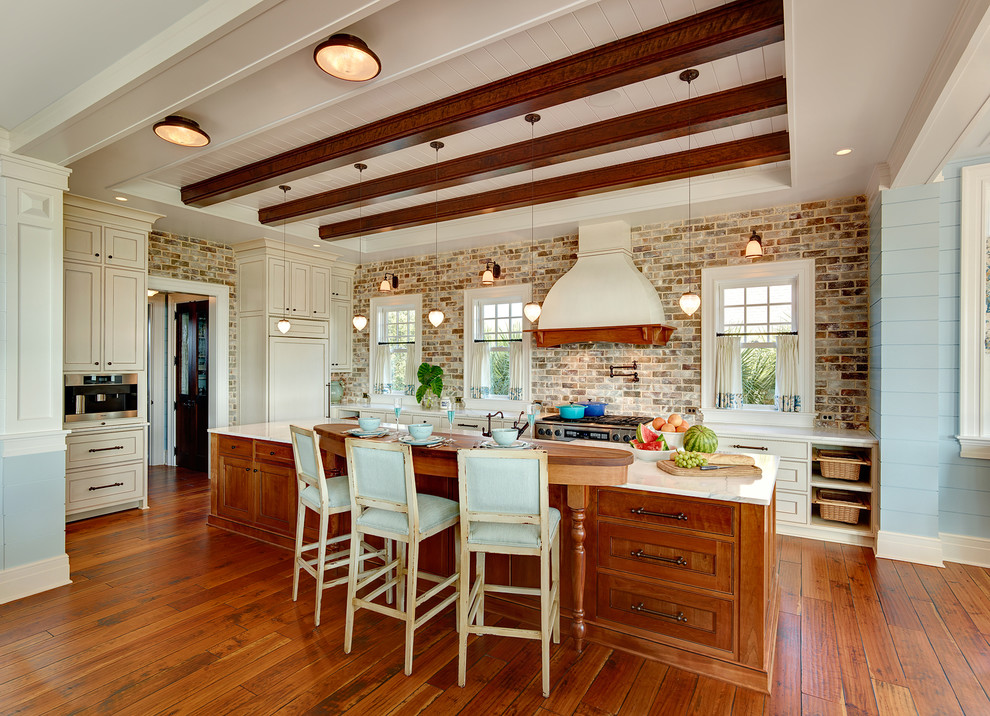 Maritime Küche in L-Form mit weißen Schränken, Elektrogeräten mit Frontblende und braunem Holzboden in Charleston