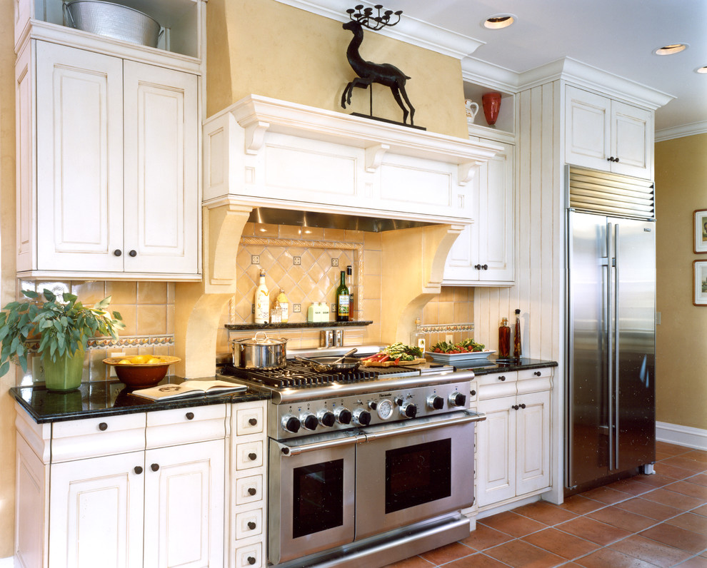Foto på ett stort medelhavsstil kök, med en nedsänkt diskho, luckor med upphöjd panel, vita skåp, träbänkskiva, gult stänkskydd, stänkskydd i keramik, rostfria vitvaror, klinkergolv i terrakotta och en halv köksö