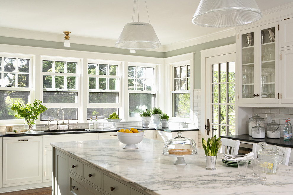 Klassische Küche mit Glasfronten, weißen Schränken, Küchenrückwand in Weiß und Rückwand aus Metrofliesen in Minneapolis